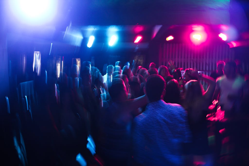 Aktuelles Bild: Vibrant nightclub scene with blurred dancing crowd and colorful lights.